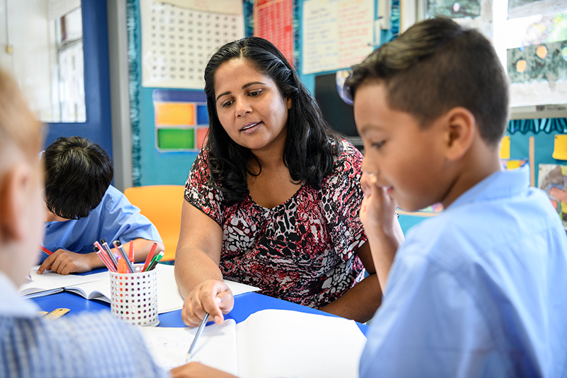 Australian female primary school teacher working with children offering support and guidance